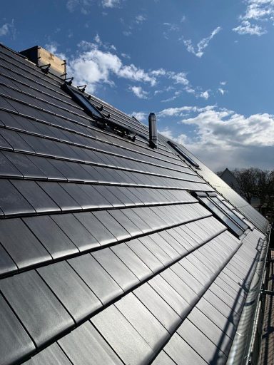 Wohnhaus Mainz Oberstadt Dach mit modernen Dachziegeln und Solarpanelen unter blauem Himmel.
